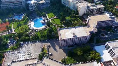 Budva bir kuş bakışı ile. Becici. Dron bir yükseklikten fotoğraf çeker. Deniz, gökyüzü, objektif eski tarzda ev sahipliği yapmaktadır. Kahverengi çatılar tatil beldesi. Modern otel deniz kenarında. Bağlantı noktası ile demirli yatlar.