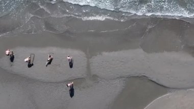 Beş kişi kum yazma: Karadağ. Uçak dikey olarak aşağı vuruyor. Siyah kum denize yakın.