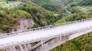 Nehrin Tara Karadağ ile bir bird's-eye Kanyonu. Dzhurdzhevich Köprüsü. Drone etrafında duran insanlar köprüde uçar. Beyaz taştan kayalarla çevrili iki yanda ağaçları ile büyümüş.