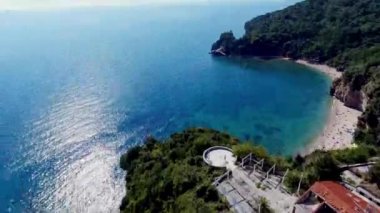 Budva bir kuş bakışı ile. Becici. Dron bir yükseklikten fotoğraf çeker. Deniz, gökyüzü, objektif eski tarzda ev sahipliği yapmaktadır. Kahverengi çatılar tatil beldesi. Modern otel deniz kenarında. Bağlantı noktası ile demirli yatlar.