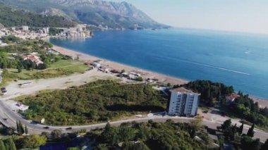 Budva bir kuş bakışı ile. Becici. Dron bir yükseklikten fotoğraf çeker. Deniz, gökyüzü, objektif eski tarzda ev sahipliği yapmaktadır. Kahverengi çatılar tatil beldesi. Modern otel deniz kenarında. Bağlantı noktası ile demirli yatlar.