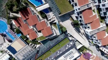 Budva bir kuş bakışı ile. Becici. Dron bir yükseklikten fotoğraf çeker. Deniz, gökyüzü, objektif eski tarzda ev sahipliği yapmaktadır. Kahverengi çatılar tatil beldesi. Modern otel deniz kenarında. Bağlantı noktası ile demirli yatlar.