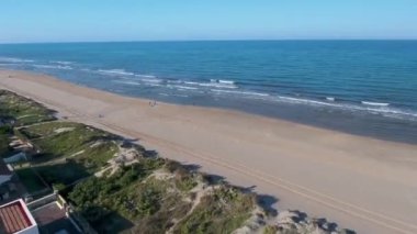 Sandy beach İspanya bir kuş bakışı ile. Uçak sahil uçar ve kıyı kum isabet dalgalar kaldırır. Lens Dnia İspanya'nın kıyı zone otelleri alır. Açık gökyüzü, temiz kum.