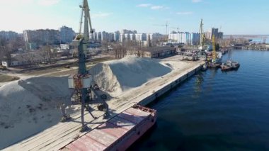 Nehir kıyısında bir kule vinç hava dron görüntüleri. Nehir ve kargo liman kuşbakışı. Drone liman nehir kumu yüklenmesini, kule vinç kaldırır. Cherkassy, Ukrayna