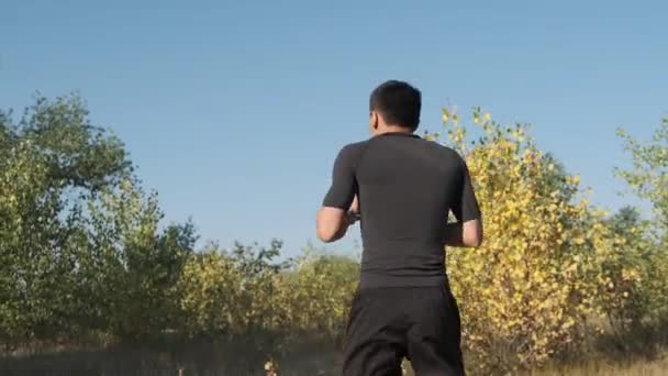 公園で若いスポーツマンボクサーとキックバックトレーニング 若い男はキックのテクニックを働かします — ストック動画