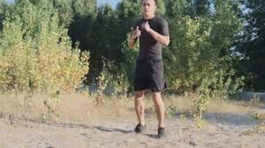 Parkta genç bir sporcu boksörü ve geri dönüş eğitimi. Genç adam tekme tekniği çalışır