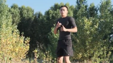Parkta genç bir sporcu boksörü ve geri dönüş eğitimi. Genç adam tekme tekniği çalışır