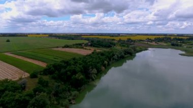 Bir kuş gözleri ile göl üzerinde Ukrayna köyü. Drone göl üzerinde uçar ve yakındaki köyde özel evler vardır. Yaz, bulutlu hava