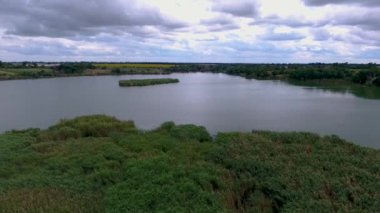 Bir kuş gözleri ile göl üzerinde Ukrayna köyü. Drone göl üzerinde uçar ve yakındaki köyde özel evler vardır. Yaz, bulutlu hava