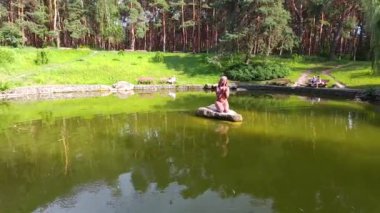 Parkta bronz heykeli olan göl. Sakin havalarda insansız hava aracını vurmak. Çamlar ve sığ göl.