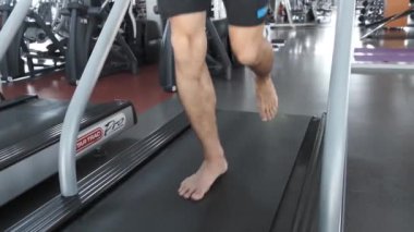 Genç Asyalı adam spor salonunda koşu bandında koşuyor. Kickboksçu, beyaz tişörtlü genç bir adam. Kolay çalıştırma.