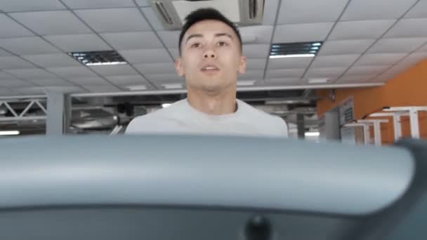年轻的亚洲小伙子在健身房的跑步机上跑步 拳击手 一个穿白色T恤的年轻人 轻松运行 — 图库视频影像