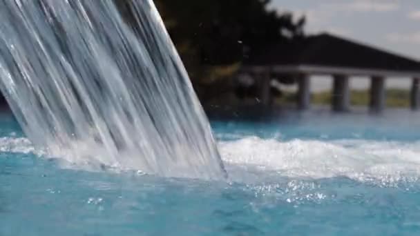 空の下のプールの滝クローズアップ 水はゆっくりとプールに落ちる 美しい背景 バックライト付き青い水 — ストック動画