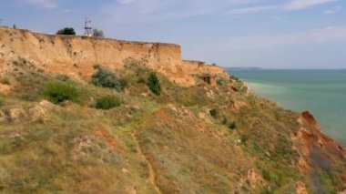Yuzhny Odessa limanı yakınlarındaki Karadeniz 'in sarp kıyısı kuş bakışı. İHA saldırısı. 2020 yazında. Denize yakın 30 metre yüksekliğinde bir uçurumu olan kumsal. Çimler güneşin altında kurudu. Kavurucu güneş ve açık gökyüzü.