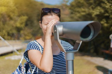 Sonbaharda Stagira Yunanistan 'daki Aristo' nun parkındaki sahneyi izlemek için tek gözlü teleskop dürbünü kullanan genç kadın turist.