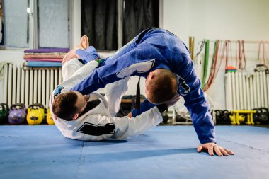Brezilyalı Jiu Jitsu BJJ dövüş sanatları eğitimi akademide iki dövüşçü tersten Riva Muhafız pozisyonu alıyor.