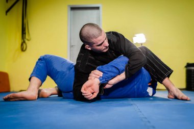 Brezilyalı Jiu jitsu BJJ jiujitsu antrenman antrenmanı sporcusu rakibine omuz kitleme tekniği uygulaması yapıyor.