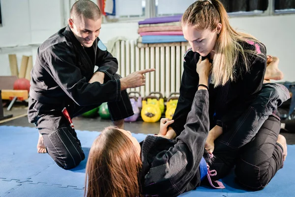 Brezilyalı JIu Jitsu BJJ dövüş sanatları akademisi özel ders profesörü. Kimono gi 'deki kız öğrencileriyle teknik detaylar üzerinde çalışıyor.