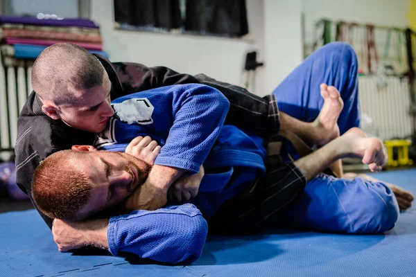 Brezilyalı Jiu jitsu BJJ jiujitsu idman antrenmanı sporcusu ölümcül antreman dövüşçüsü boğma mata leao teslimiyetini rakip teknikte kimono gi giyerek uyguluyor.