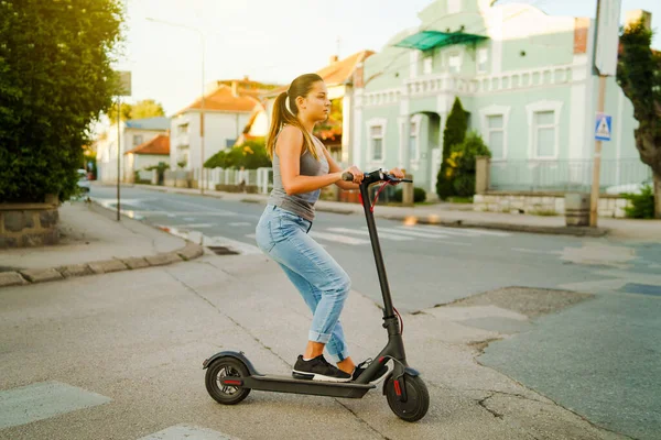 Młoda Kobieta Jeździ Elektrycznym Hulajnoga Ulicy Czeka Skrzyżowaniu Dżinsach Letni — Zdjęcie stockowe