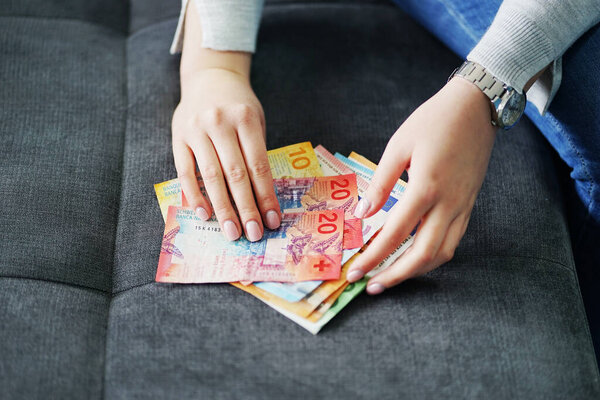 Woman counting euro and CHF banknotes salary family budget savings