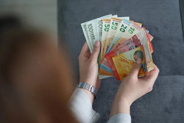 home house family budget woman holding euro and CHF banknotes money in hands at home counting salary