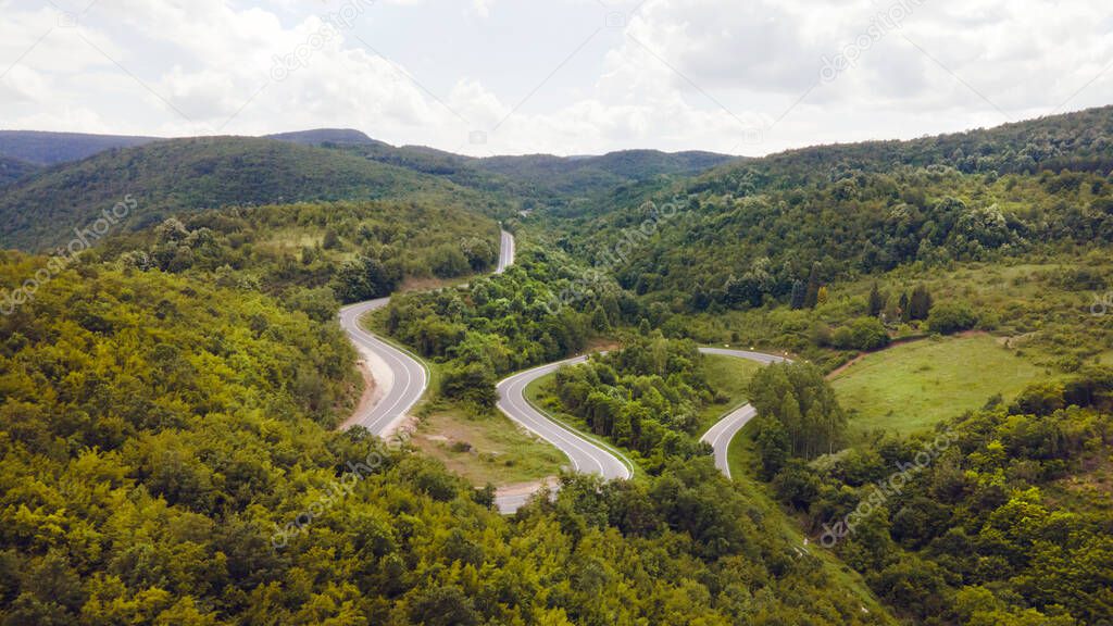 Aerial view drone image of curvy mountain road asphalt with serpentine trough the trees green forest in day in summer or autumn nature taken in Serbia Tresibaba Knjazevac in Balkans