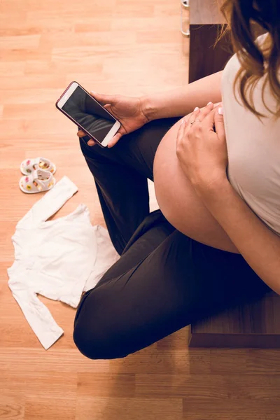 High angle view on pregnant woman mother holding mobile phone calling hospital for delivery birth baby emergency doctor