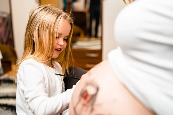 Kleines Blondes Mädchen Bemalt Schwangerschaftsbauch Ihrer Mutter Mit Wasserfarben — Stockfoto