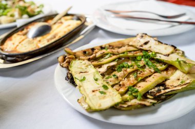 Kabak kabağı yaz kabağı salatasına yakın. Masada sarımsak ve yağ var.