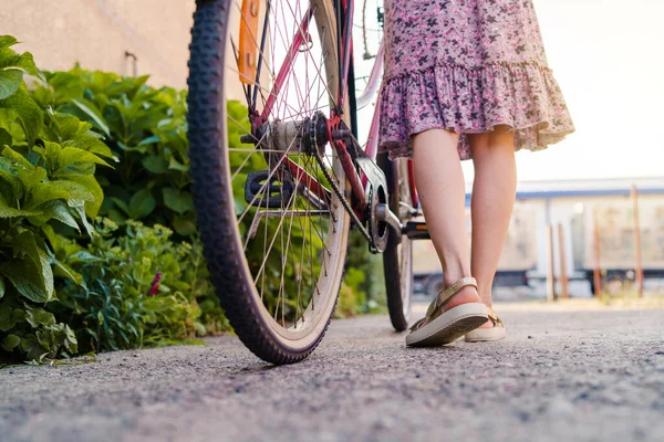 晴れた日に夏のドレスを着て自転車の横に立つ女性の足の上に閉じます — ストック写真