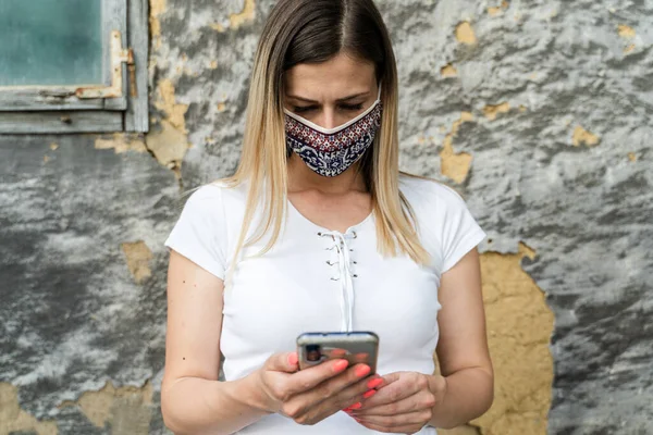 成年白种人女性因头孢病毒爆发而戴防护面具的肖像 现代女性社交距离病毒预防 手机在线发短信或应用 新的正常概念 — 图库照片