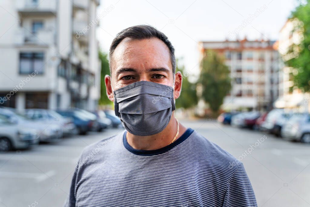 Portrait of adult caucasian man wearing protective mask due to coronavirus outbreak - MIddle aged modern male social distance virus prevention - Front view in day outdoor - The new normal concept