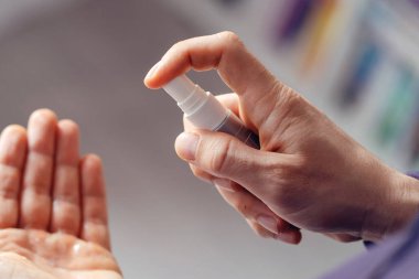 Yüksek açı, bilinmeyen erkek, beyaz adam sprey dezenfekte alkol ürünü uyguluyor. Evde ya da iş yerinde virüs bakterisi sağlığını önlemek için elleri dezenfekte ediyor.