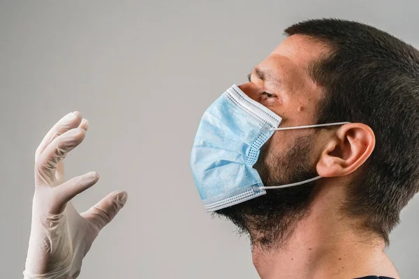 Close up portrait of caucasian man adult wearing anti-virus bacteria pollution protective mask head shot studio shot side view holding hands with gloves near face disease threatened to choke