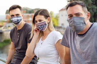 Beyaz tenli turistler koruyucu maskeler takarak seyahate çıkıyorlar. Covid-19 salgınından dolayı sosyal mesafeler ve önlem alıyorlar. Kafkas dostları yeni normal yaşam tarzı kavramını kapatıyorlar.