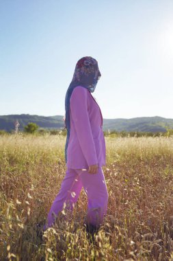 Mor takım elbiseli, kimliği belirsiz bir kadının portresi. Güneşli yaz günlerinde ya da akşamlarda sahada kafasında eşarpla yürüyor. Kimlik ve doğa karmaşası kavramı.
