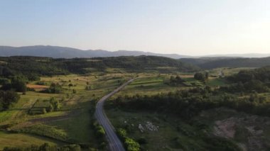  Dağ sırasındaki dağ yolunda yukarıdan bakıldığında yeşil çimenler ve etraftaki ağaçlar arasında hava manzarası - Sırbistan 'ın Tresibaba kentindeki hava aracı videosu güneşli yaz günü veya akşam saatlerinde Sırbistan' da
