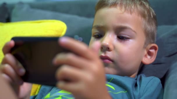 Piccolo Ragazzo Caucasico Sdraiato Sul Divano Letto Casa Utilizzando Smartphone — Video Stock