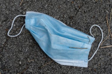 Gündüz vakti asfalta fırlatılan tıbbi koruyucu maske. Atık Covid-19 Coronavirüs. Yeni normal konsept çevre kirliliği önleyici bakım ve salgın hastalık yayılımı.