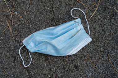 Gündüz vakti asfalta fırlatılan tıbbi koruyucu maske. Atık Covid-19 Coronavirüs. Yeni normal konsept çevre kirliliği önleyici bakım ve salgın hastalık yayılımı.