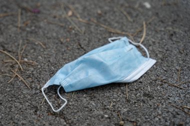 Gündüz vakti asfalta fırlatılan tıbbi koruyucu maske. Atık Covid-19 Coronavirüs. Yeni normal konsept çevre kirliliği önleyici bakım ve salgın hastalık yayılımı.