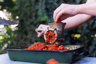 Balkan 'da sağlıklı organik gıda kavramı olan ayvar ulusal yemeği için kırmızı biber hazırlayan sebzeler için öğütücü değirmenindeki kadın eli kapalı.