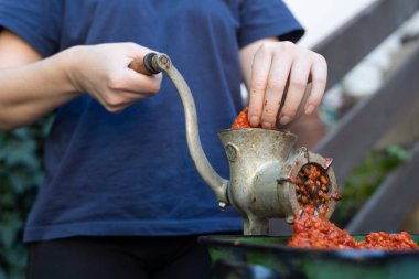 Balkan 'da sağlıklı organik gıda kavramı olan ayvar ulusal yemeği için kırmızı biber hazırlayan sebzeler için öğütücü değirmenindeki kadın eli kapalı.