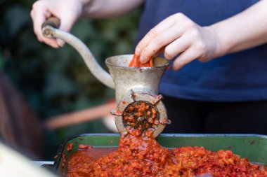 Balkan 'da sağlıklı organik gıda kavramı olan ayvar ulusal yemeği için kırmızı biber hazırlayan sebzeler için öğütücü değirmenindeki kadın eli kapalı.