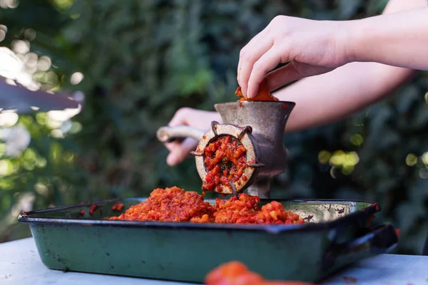 Balkan 'da sağlıklı organik gıda kavramı olan ayvar ulusal yemeği için kırmızı biber hazırlayan sebzeler için öğütücü değirmenindeki kadın eli kapalı.