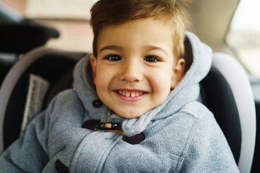 Arabasında oturan, gülümseyen küçük beyaz çocuğa yaklaş.