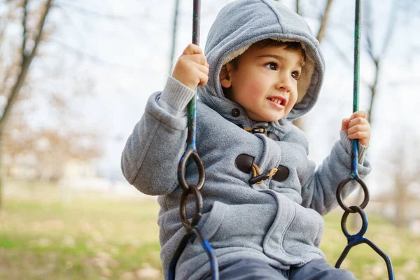 秋の日に一人で楽しむ公園で揺れる冬のコートで小さな白人の少年にサイドビュー コピースペースレジャー活動の概念を成長 — ストック写真