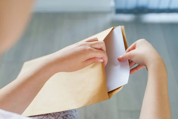 Close up on hands of unknown caucasian woman hold envelope opening or sending letter with mail or documents at home in day top view