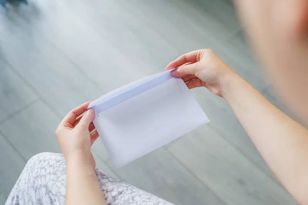 Close up on hands of unknown caucasian woman hold envelope opening or sending letter with mail or documents at home in day top view